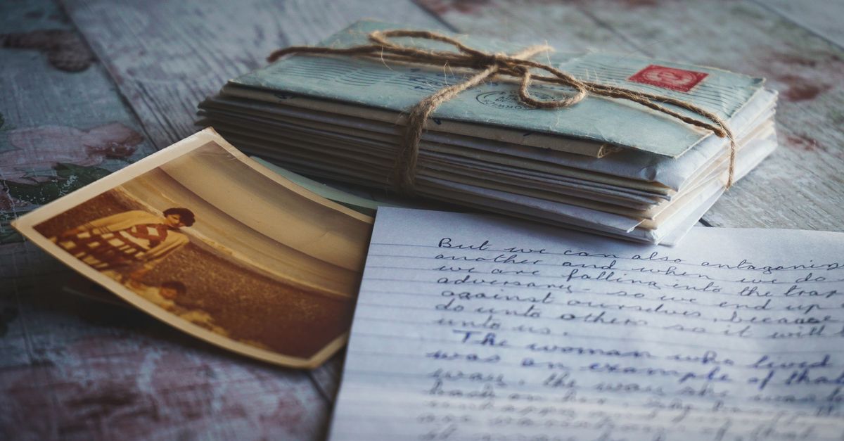 Handwritten letters and envelopes spread across a wooden desk